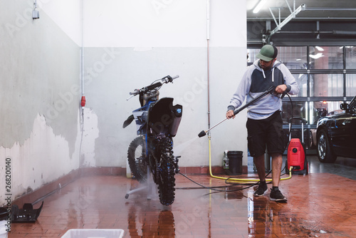 Man Cleans his motocross bike with pressure washer photo