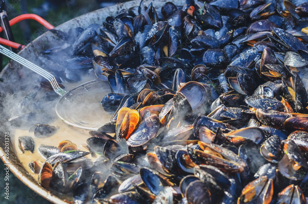 Mussels roasted on a grill pan. Seafood cooked outdoors. Selective focus
