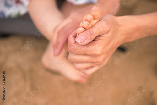 mother's hands wipe children's feet from the sand © Anna Belova