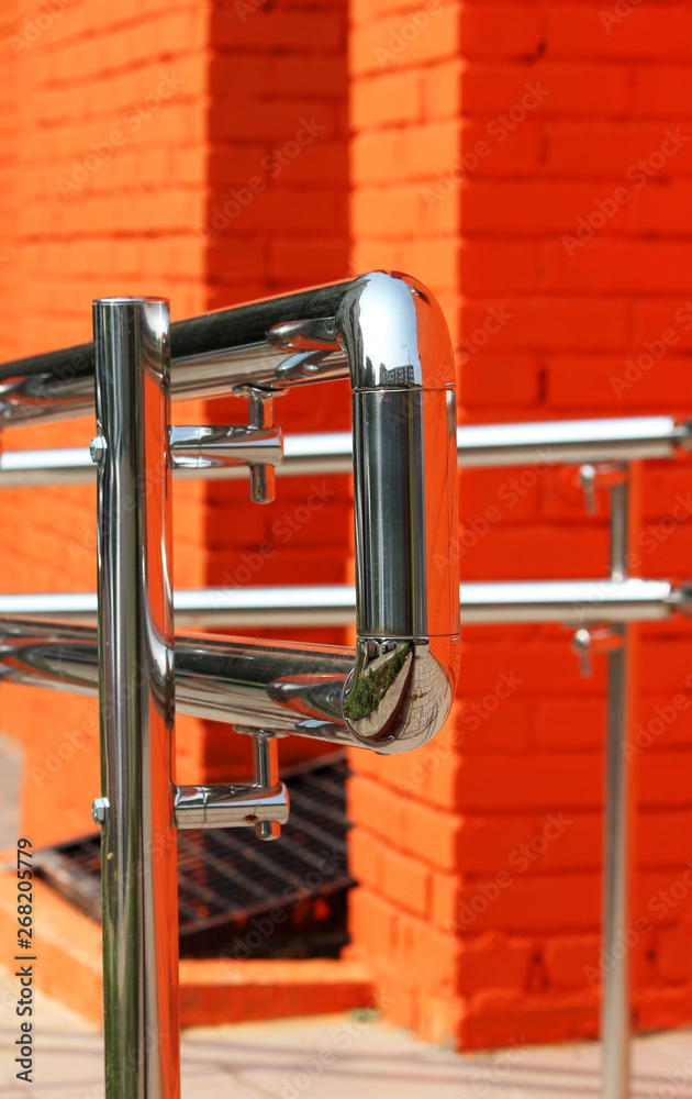 Metal steel handrail with a exit for invalid near the premises. Brick wall painted with orange paint Metal steel handrail with a exit for invalid near the premises. Brick wall painted with orange paint