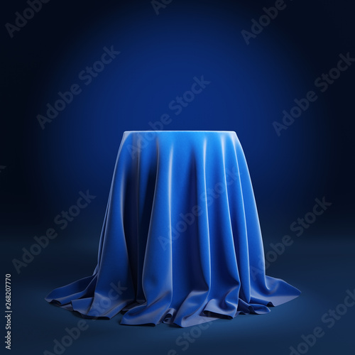 Round podium covered with blue cloth on a blue background. 