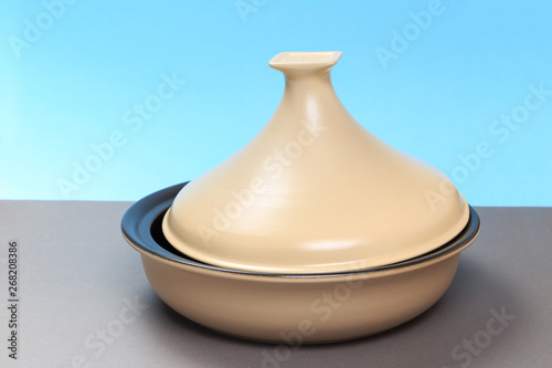 A new ceramic pan stands on a gray table and a blue background. close-up