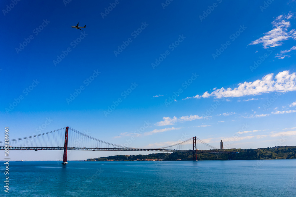 25 April Bridge over the Tagus river and airplane in the sky in Lisbon