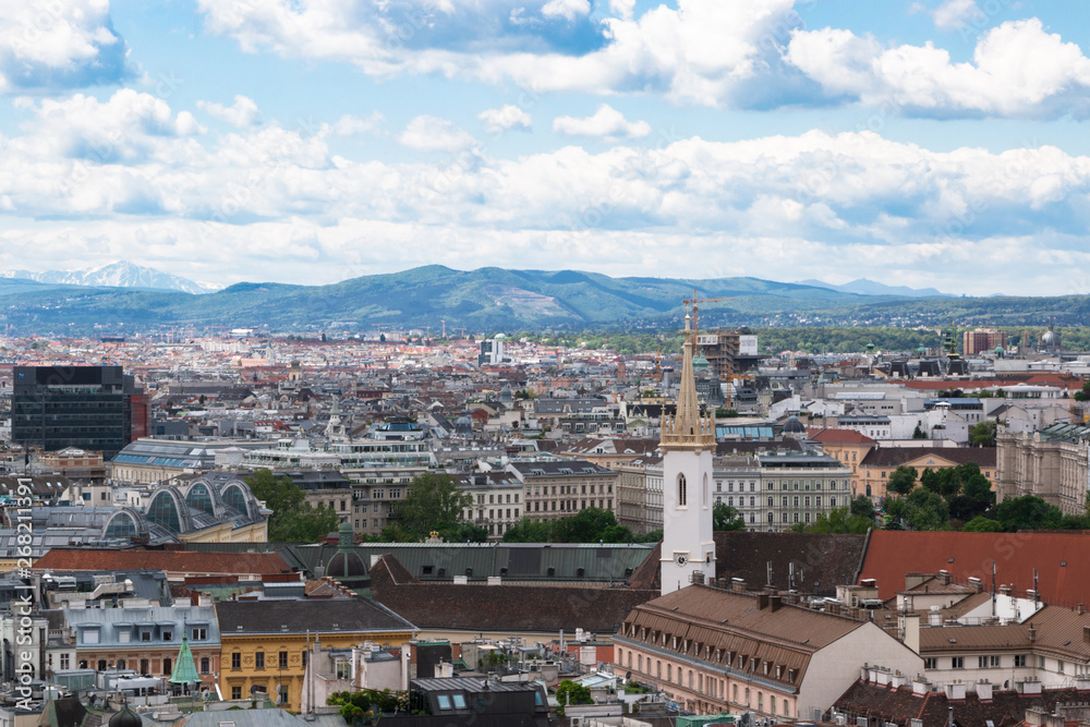 Wien, Austria. May, 2019. Panorama of the city from the observation tower of St. Stephen’s Cathedral. Roofs of houses. In the distance, the Alpine Mountains. Sky view.