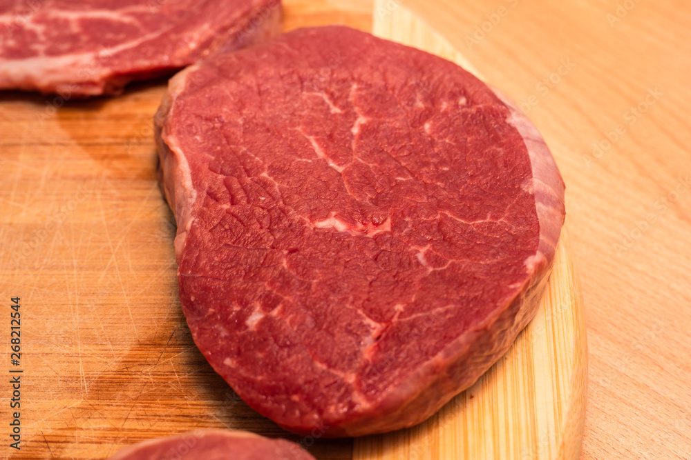 Raw Steaks on a cutting board on a wooden background. fresh meat, top view Raw Steaks on a cutting board on a wooden background. fresh meat, top view