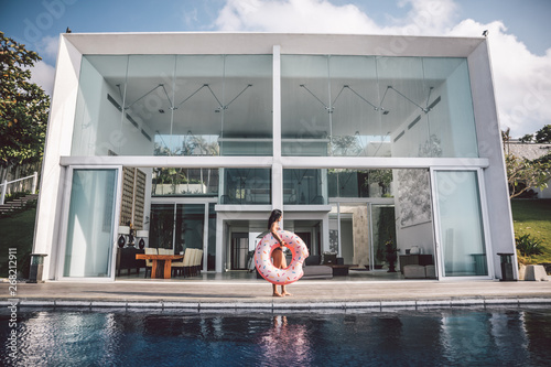 beautiful woman with inflatable pink donut in front of luxury villa photo