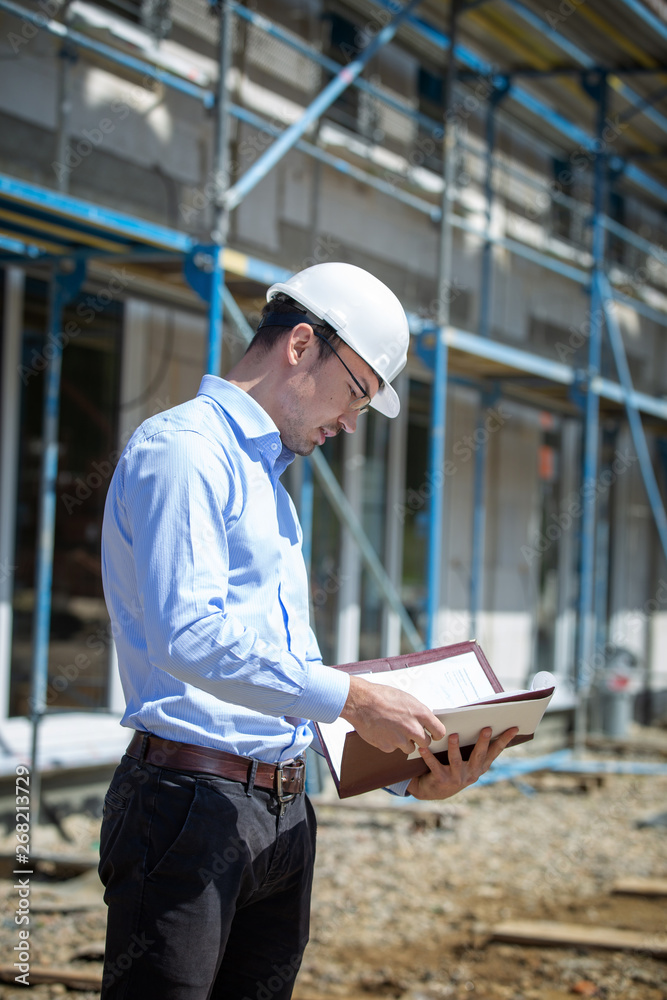 Architect inspects construction outside talking on the phone. Architect inspects construction outside talking on the phone.