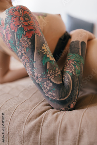 tattooed naked woman lying on the bed photo