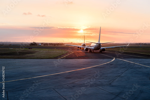 Two aircraft lined up awaiting to enter runway at sunset photo