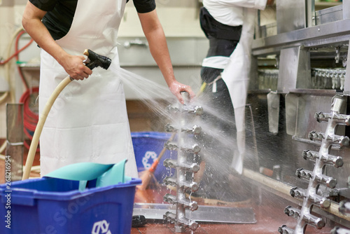 Kitchen worker cleaning components of an industrial dish washing machine