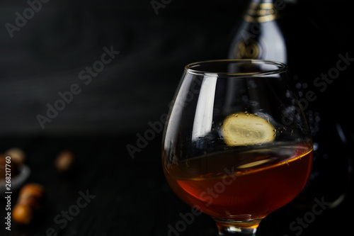 Cognac in a glass on a wooden dark background with truffles and hazelnuts