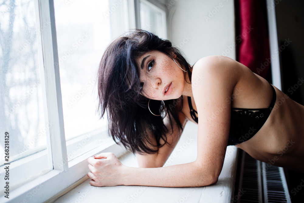 woman stands at the window, leaning on the windowsill woman stands at the window, leaning on the windowsill