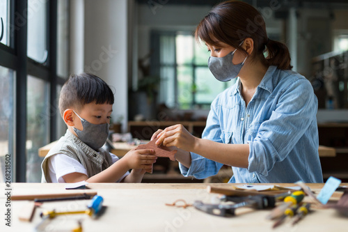 Carpenter wearing mask working with her son in workshop photo