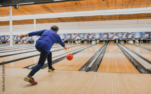 Older woman throwing bowling ball down a bowling lane. photo
