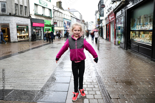 Young Girl in Pink Jacket Poses on Galway Street in the Rain photo