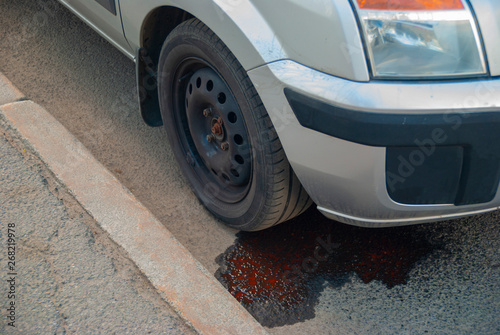 Broken car on the roadside. Oil leak from the engine on the asphalt.