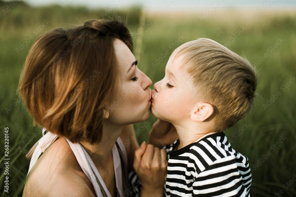Side view of mother kissing her son outdoors Side view of mother kissing her son outdoors