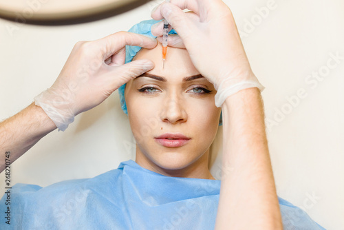 Foto Woman makes botox injections in forehead area