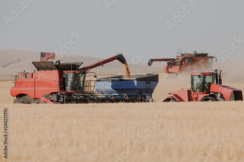 wheat combine offloading wheat to trailer