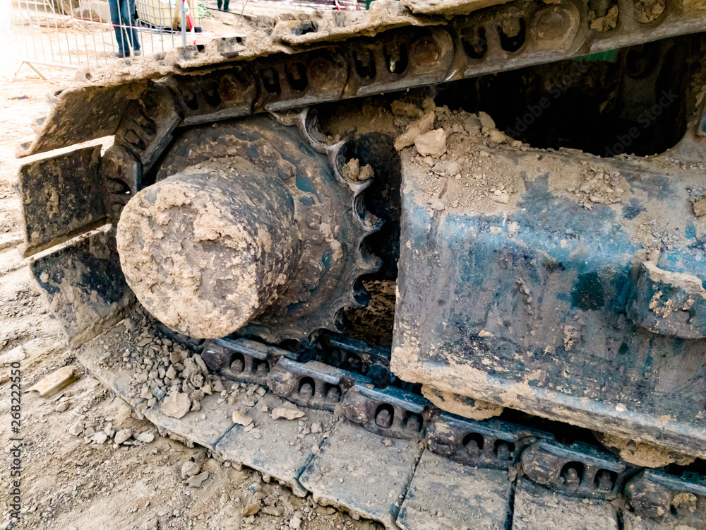 Closeup image of excavator tracks covered in dirt on the construction site Closeup image of excavator tracks covered in dirt on the construction site