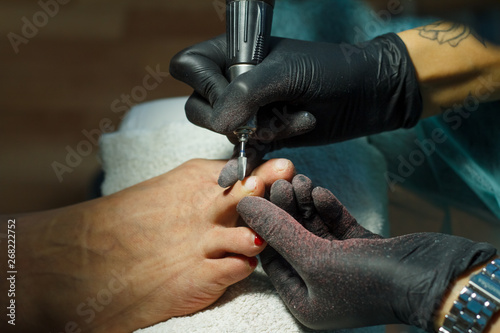 Beautician grinds the nail bar for a pedicure in the beauty salon.