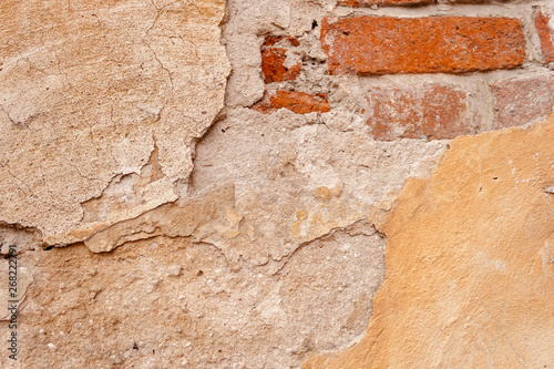 Background rough rustic shabby texture of old wall with yellow cracked plaster and vintage red brick