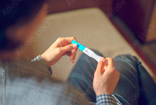 Woman holding positive pregnancy test. Close-up of hands and kit