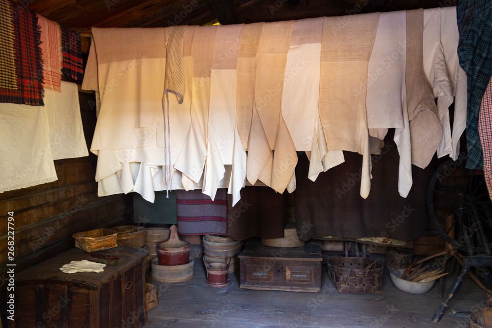 Authentic traditional linen peasant shirts from the 18th - 19th centuries, dishes, peasant household items in the interior of an old wooden peasant hut in Seurasaari in Helsinki, Finland.