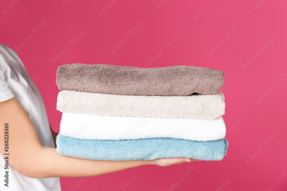 Young woman holding clean towels on color background, closeup. Laundry day Young woman holding clean towels on color background, closeup. Laundry day