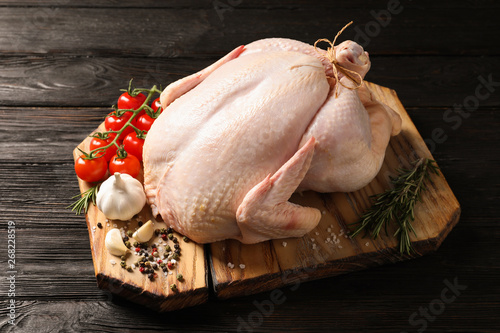 Board with raw turkey and ingredients on wooden background photo