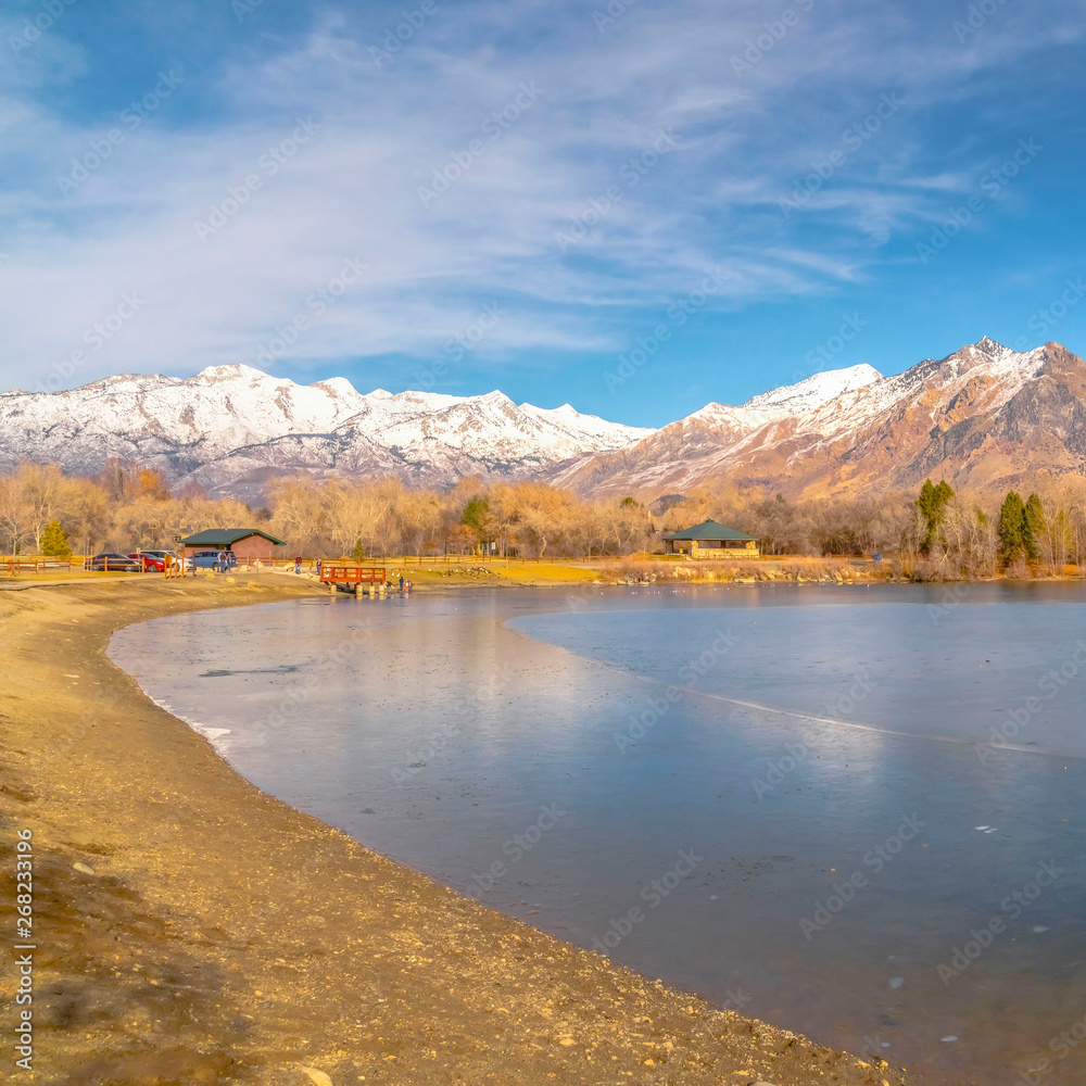 Square Scenic panorama of a lake against snow capped mountain and blue sky in winter