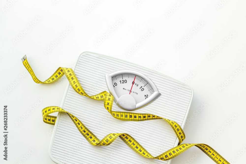 bathroom scales and measuring tape for weight loss concept on white background top view - obrazy, fototapety, plakaty 