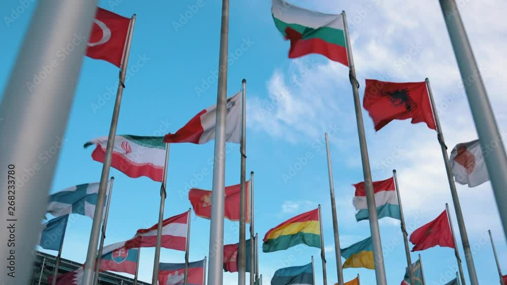 International flags of different countries waving in the wind on flagpoles - Ukrainian, Norway, Poland, Canadian, Georgian, Armenian, Lithuanian, Austrian and more