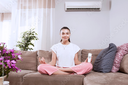 woman using remote control of air conditioner 