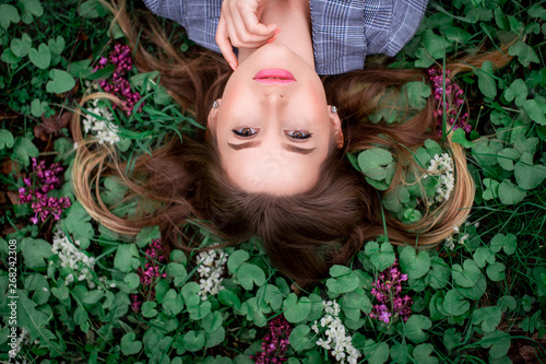 A girl with hand is lying on the grass in flowers in May 2019