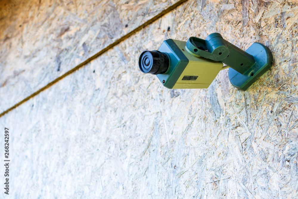 Fake security camera placed on a wooden OSB (oriented strand board) in sub-urban neighborhood. Concept for private home, security, with space for text. Fake security camera placed on a wooden OSB (oriented strand board) in sub-urban neighborhood. Concept for private home, security, with space for text.