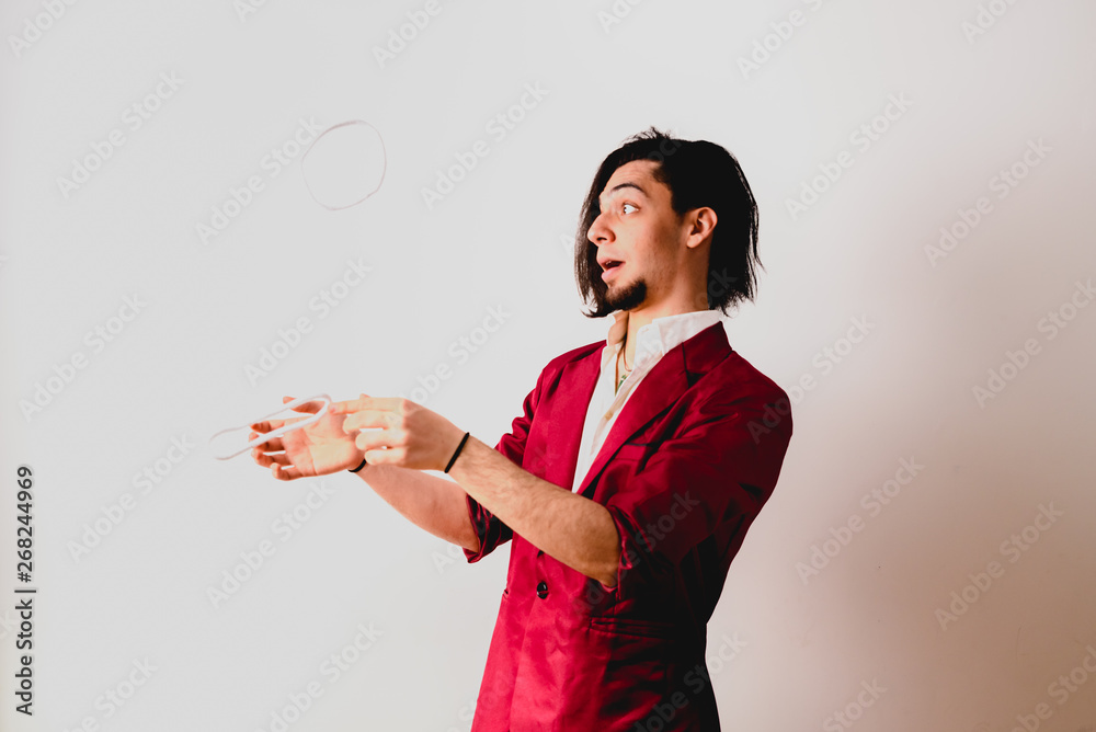 Portrait of young magician making funny gestures isolated on white background