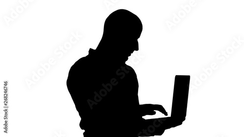 Silhouette Young middle eastern businessman, standing and typing on laptop when holding it in his hands. photo