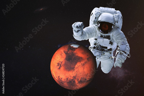 Fototapeta Naklejka Na Ścianę i Meble -  Giant astronaut near Mars planet of Solar system. Science fiction wallpaper. Elements of the image are furnished by NASA