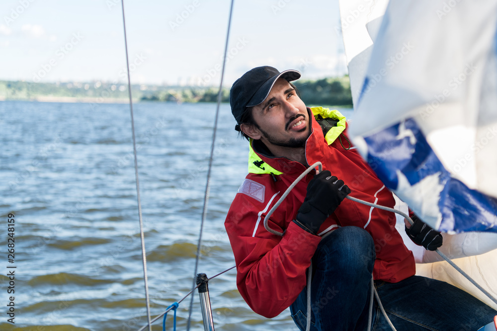 Obraz premium Yacht sailor pulling rope. Man working on sailboat.