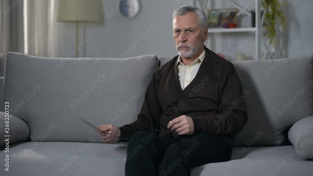 Old man sadly looking at x-ray image, difficulty coping with terminal diagnosis Old man sadly looking at x-ray image, difficulty coping with terminal diagnosis
