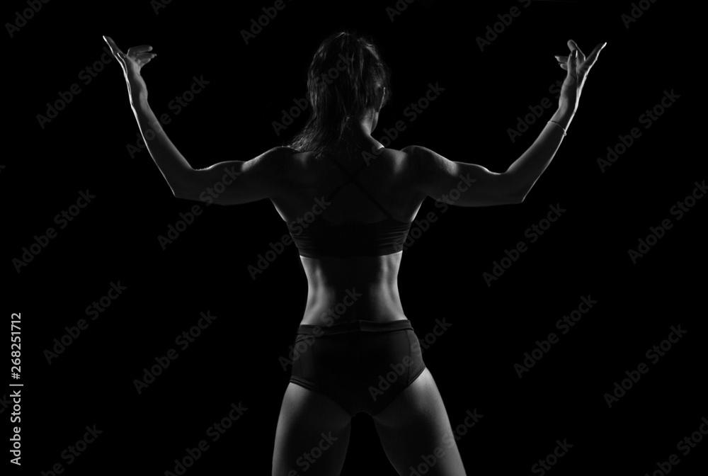 Fit woman demonstrate perfect back and shoulders on black background Fit woman demonstrate perfect back and shoulders on black background