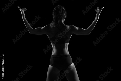 Fit woman demonstrate perfect back and shoulders on black background © Glebstock