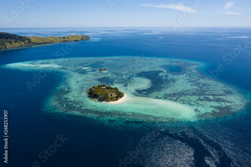 Seen from a bird's eye view, an idyllic island is surrounded by a healthy coral reef in Komodo National Park, Indonesia. This tropical area is known for its marine biodiversity as well as its dragons. © ead72