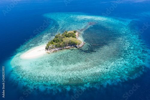 Seen from a bird s eye view  an idyllic island is surrounded by a healthy coral reef in Komodo National Park  Indonesia. This tropical area is known for its marine biodiversity as well as its dragons.