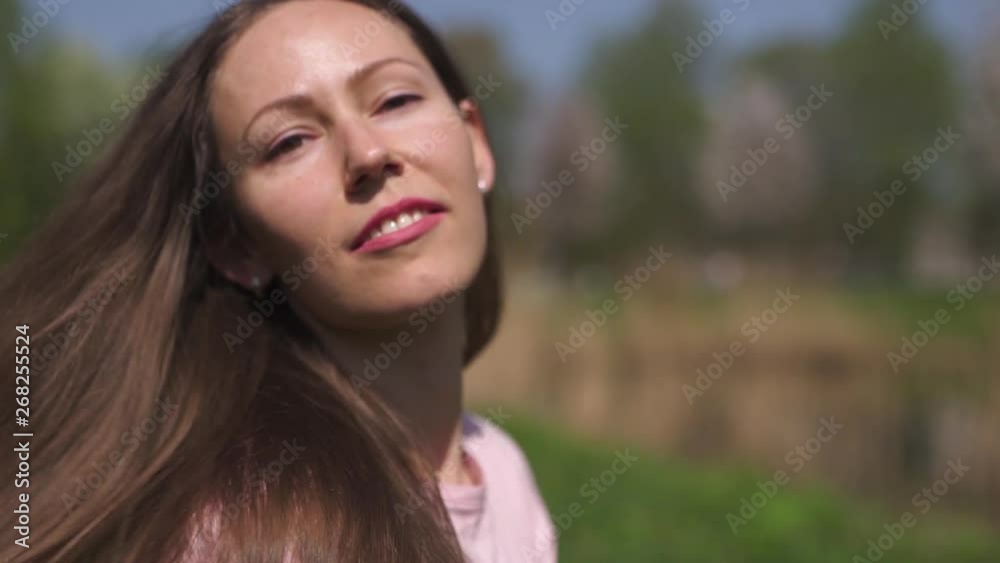 SLOW MOTION 120fps: Young happy traveler brown haired woman girl smiling and turning around in a new destination country with a pink sakura cherry blossom trees in Baltic states - Flying hair SLOW MOTION 120fps: Young happy traveler brown haired woman girl smiling and turning around in a new destination country with a pink sakura cherry blossom trees in Baltic states - Flying hair