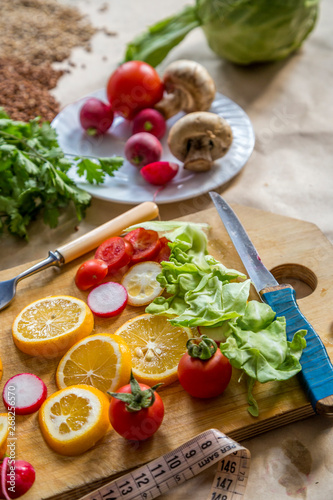 Healthy vegan food background with cutting board and lemon slices. Top view to organic food background with cutting board and lemon slices