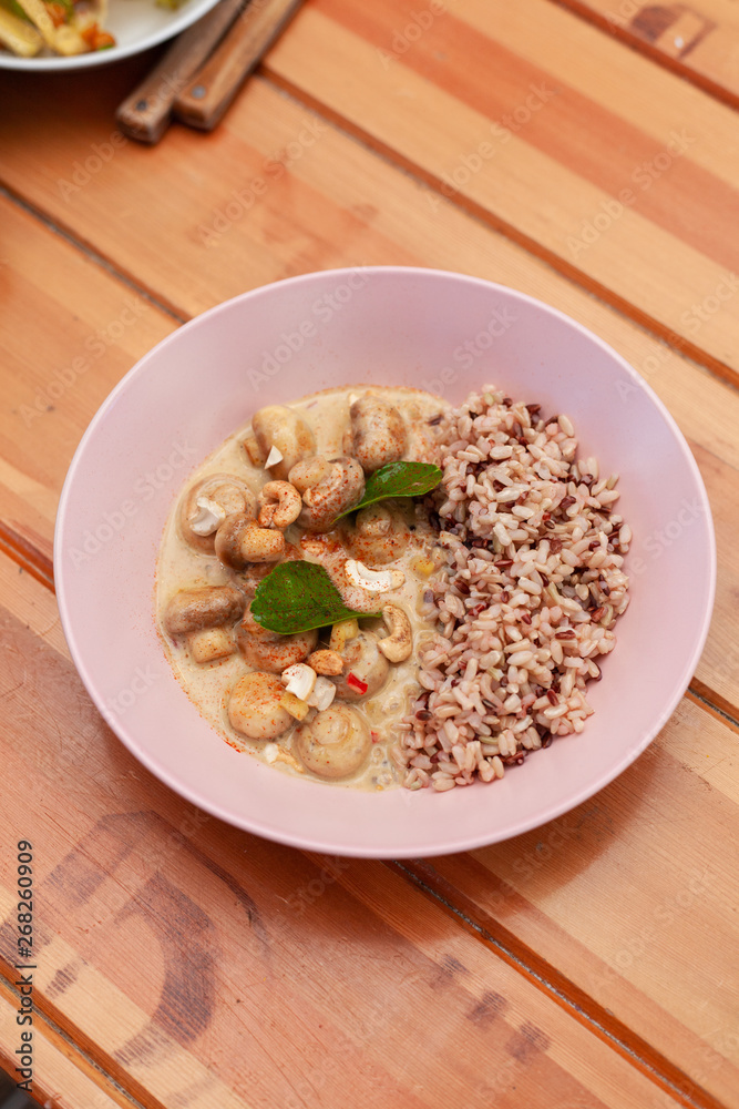 Vegetarian meal with boiled wild rice and champignons in a coconut milk gravy in a fancy pink bowl Vegetarian meal with boiled wild rice and champignons in a coconut milk gravy in a fancy pink bowl