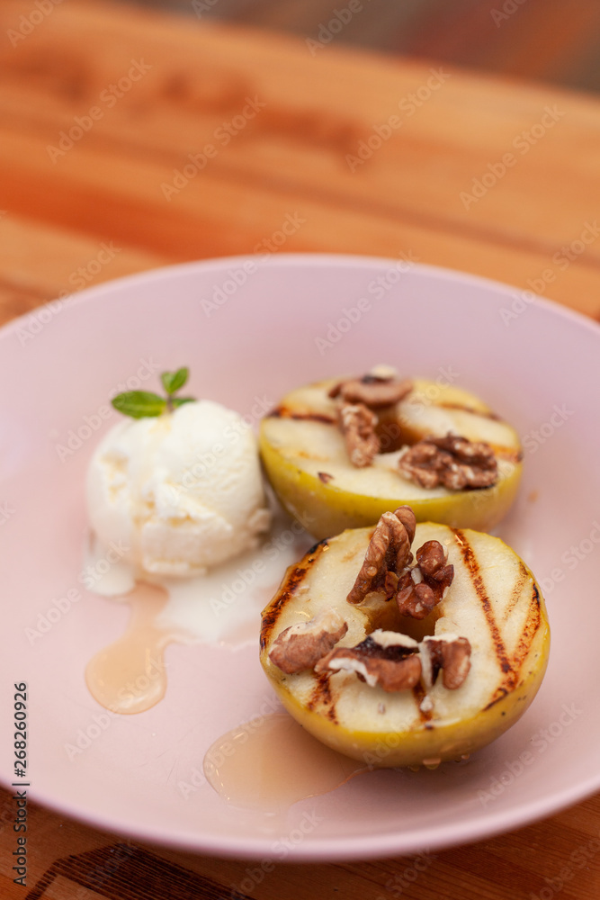 Sweet BBQ dessert: grilled apples with a nice scoop of vanilla ice cream on a light wooden table Sweet BBQ dessert: grilled apples with a nice scoop of vanilla ice cream on a light wooden table