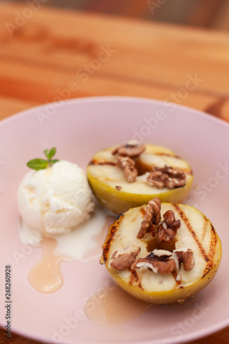 Sweet BBQ dessert: grilled apples with a nice scoop of vanilla ice cream on a light wooden table